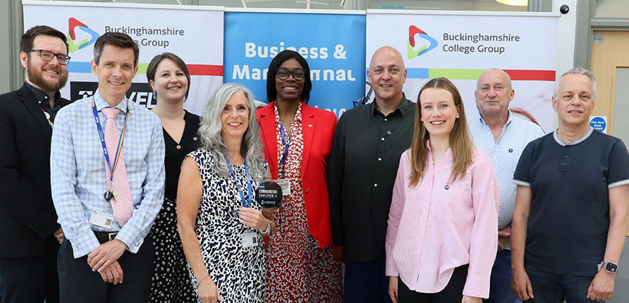 Groups of Buckinghamshire College Group staff and Mandate PR representatives standing together with glass plaque 